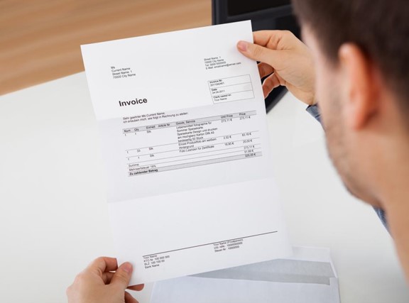 Overhead view of a young man reading an invoice document.