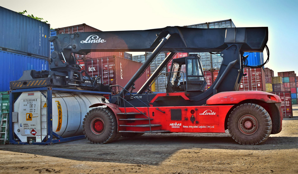 Red and black front loader beside containers